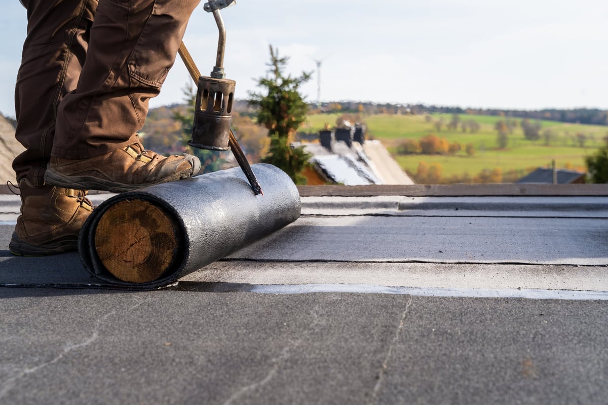 Worker installing a TPO membrane on a flat commercial roof
