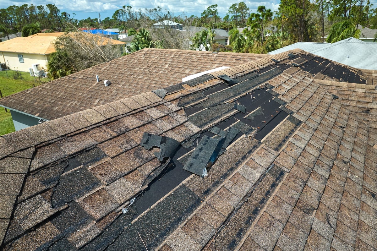 Wind-damaged roof with missing asphalt shingles after a Florida storm