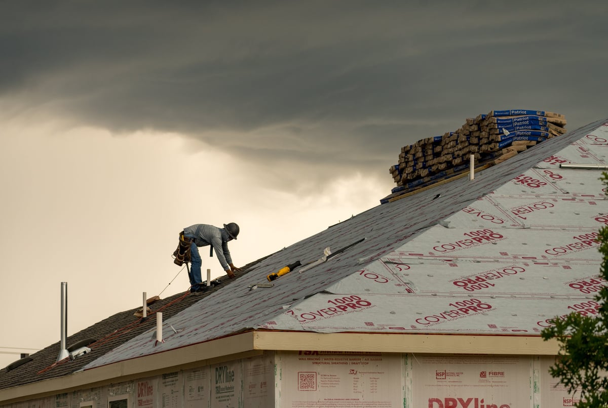 Roofer installing shingles on a new home