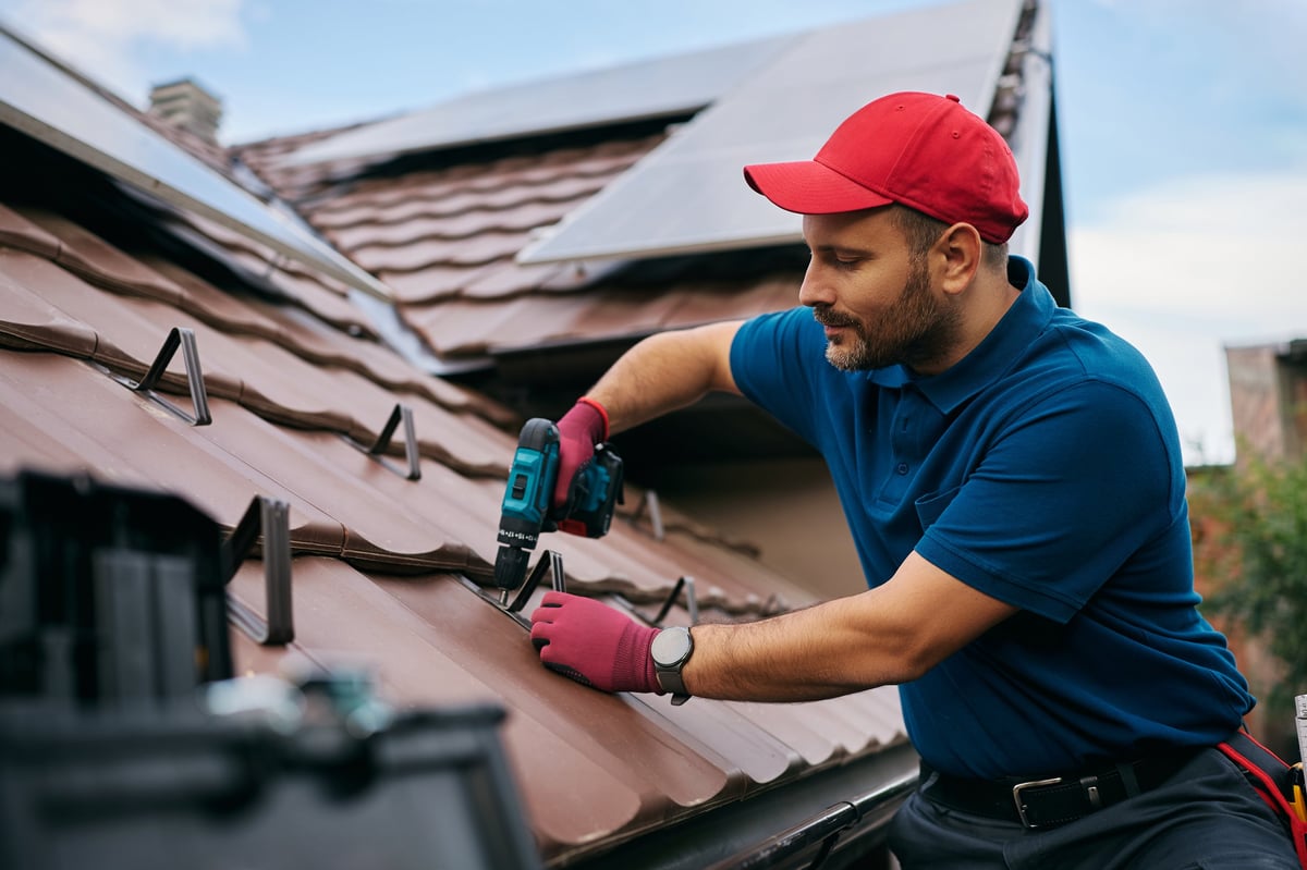 Roofer repairing asphalt shingles on a residential home roof