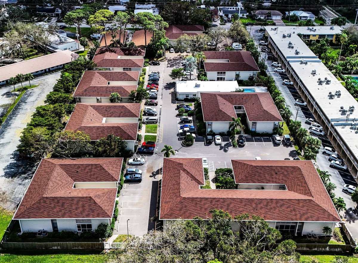 Aerial view of a condo community with red-brown architectural shingle roofs on multiple two-story buildings