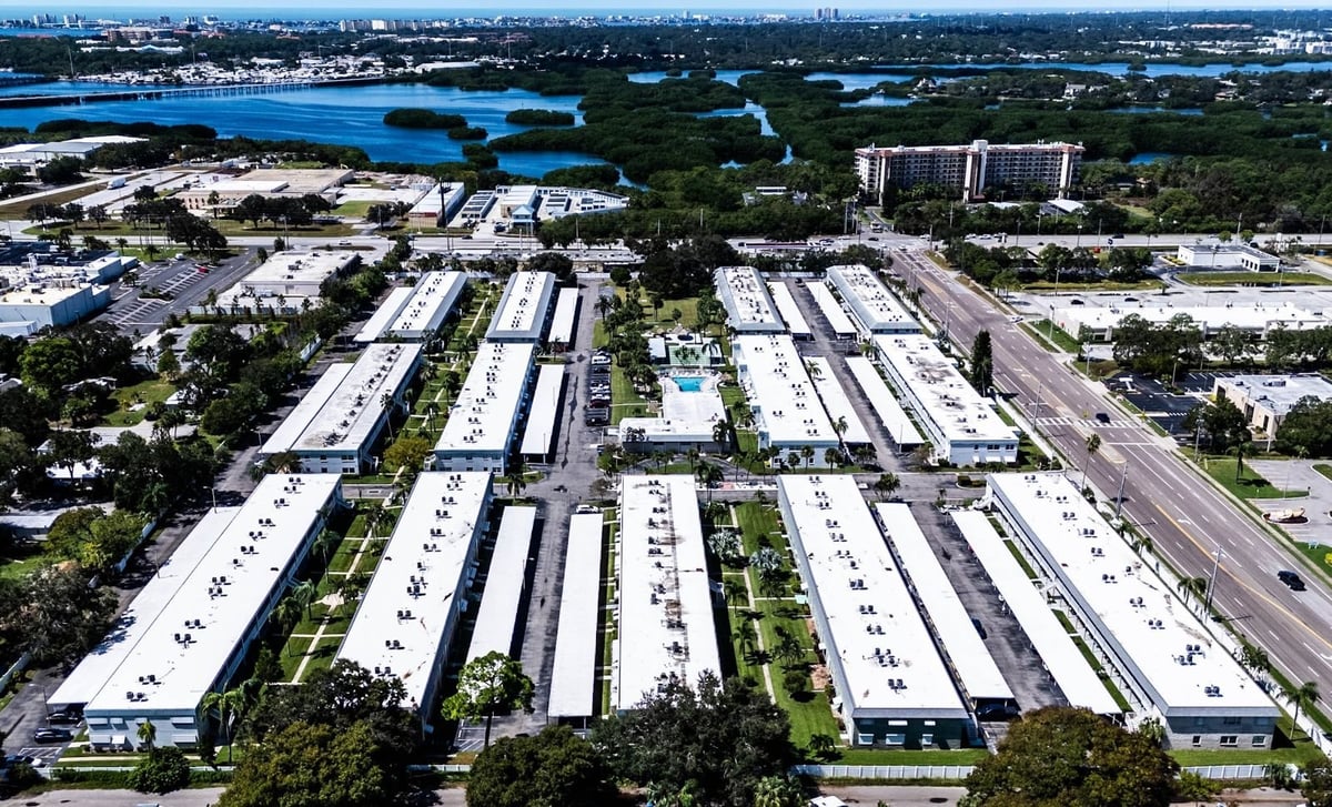 High aerial view of a condo community with rows of white flat roofs near the water